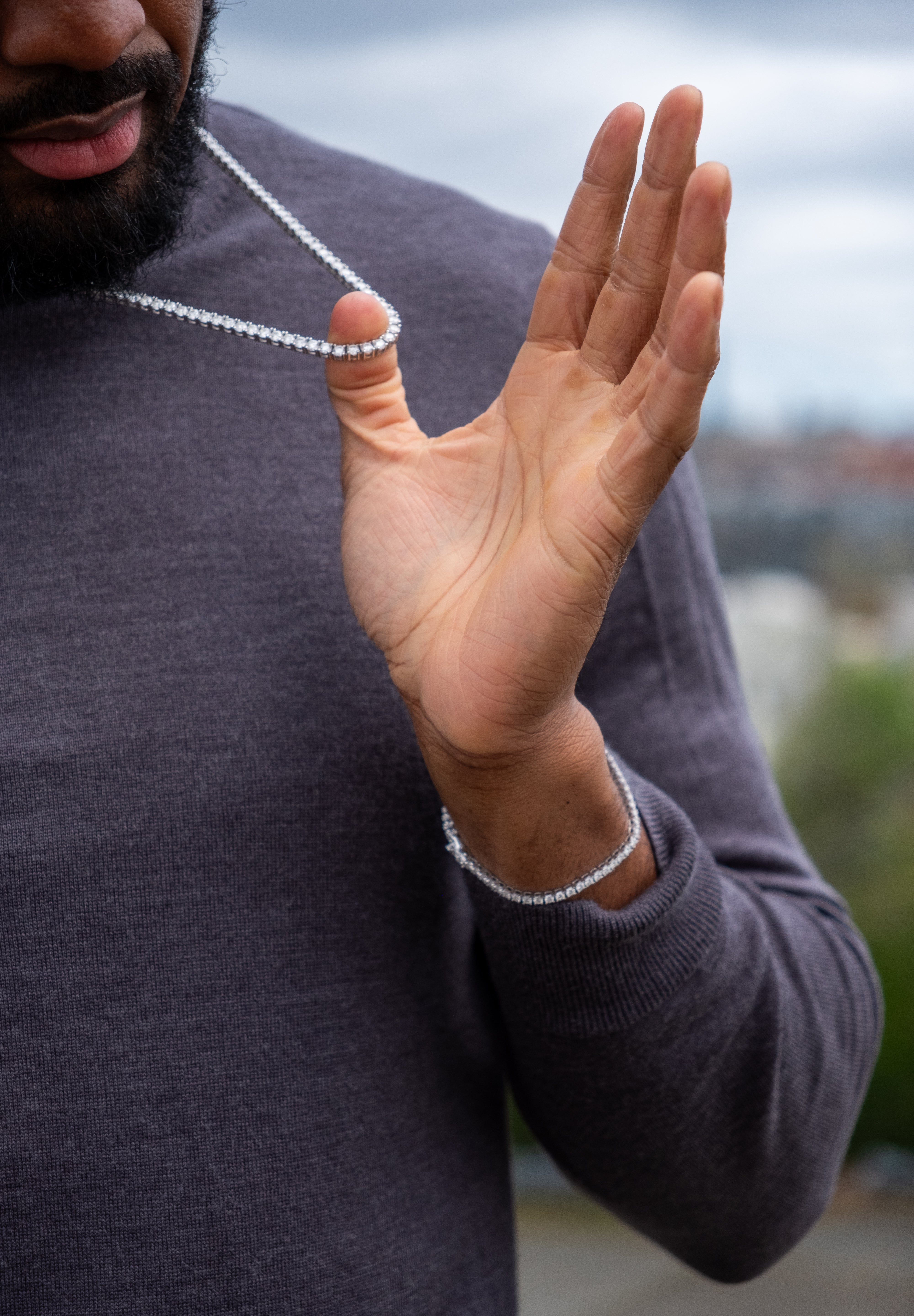A person wearing a 925 sterling silver bracelet with a tennis-style design.