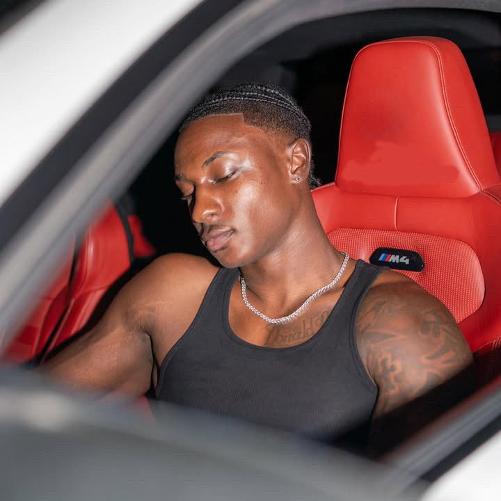 Man with chain sitting inside a car with red interior