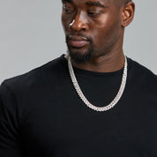 Man wearing a black shirt and white chain necklace against a gray background